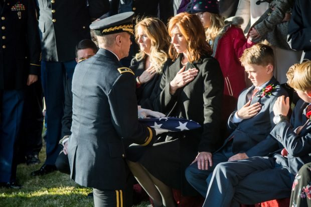 Officer kneels to present folded U.S. flag to widow,