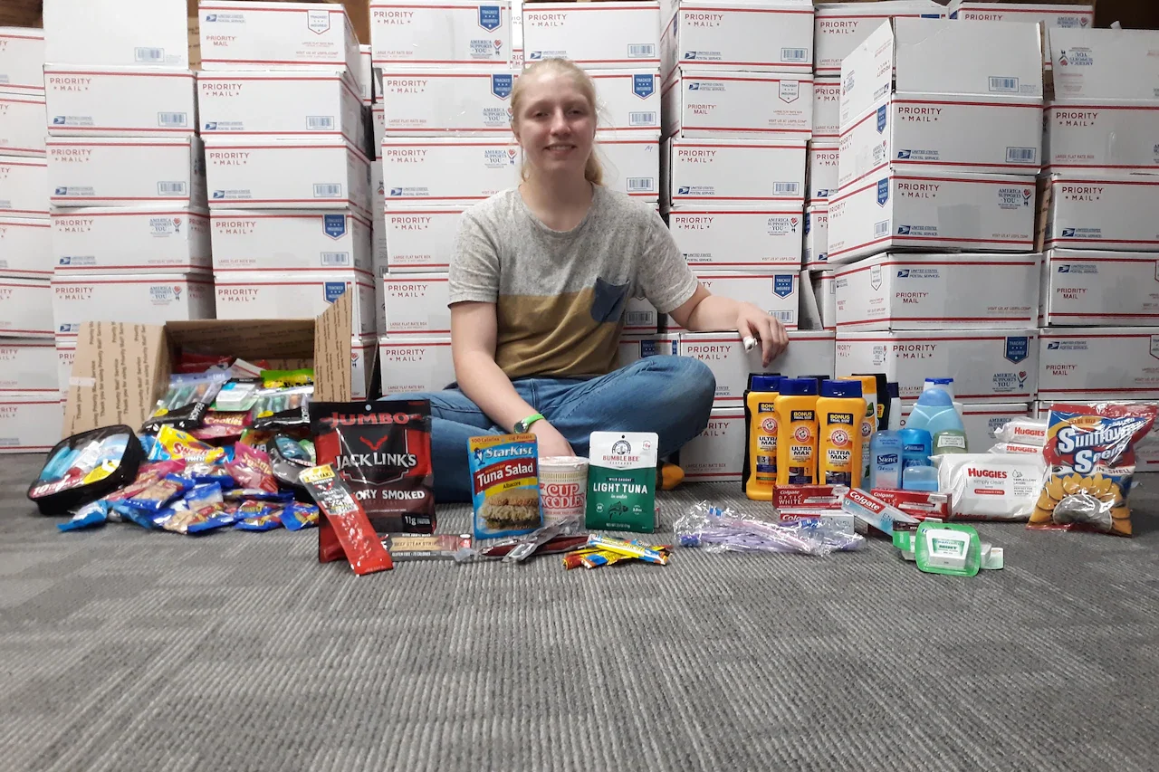 A girl poses with a care package.