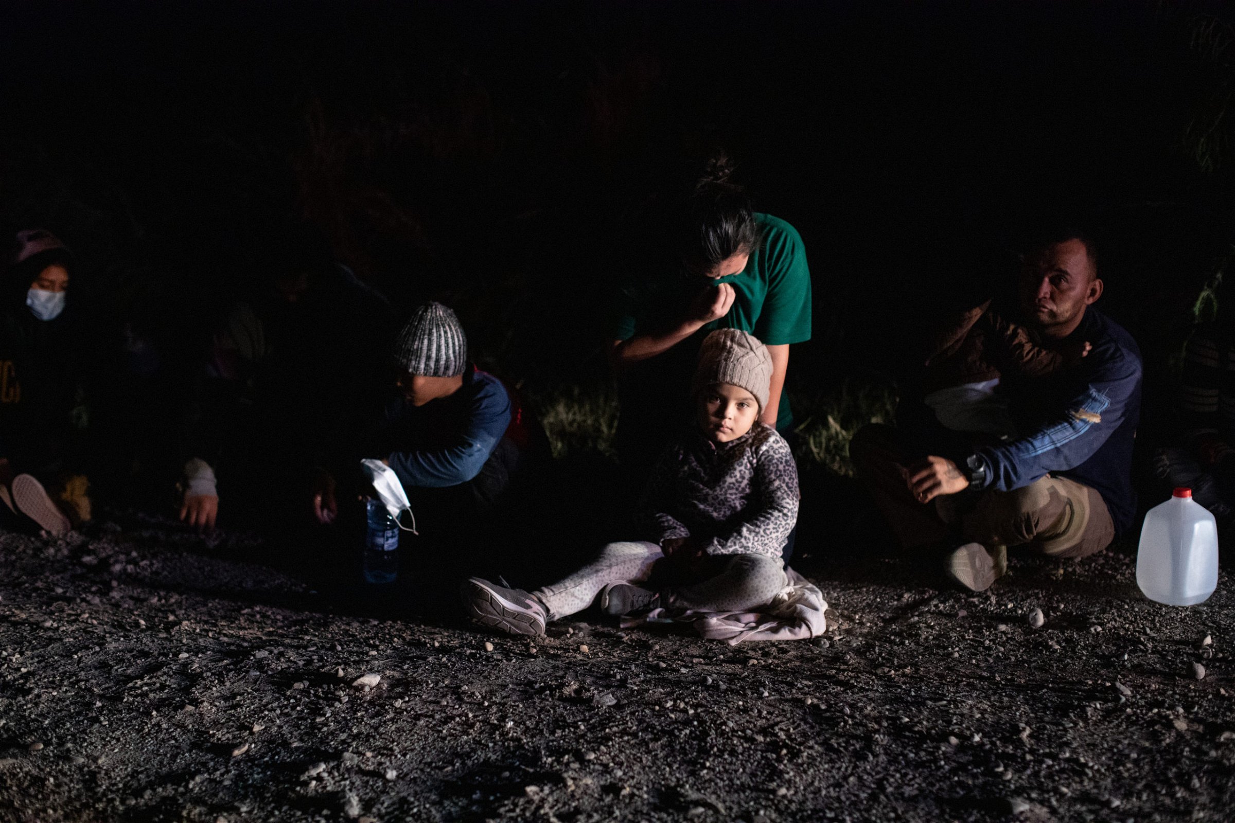 Illegal migrants sit in a line and wait to be processed by law enforcement officials who gathered biometrical data from them before transporting them to a processing facility in La Joya, Texas, on March 25, 2021. (Kaylee Greenlee. - Daily Caller News Foundation)
