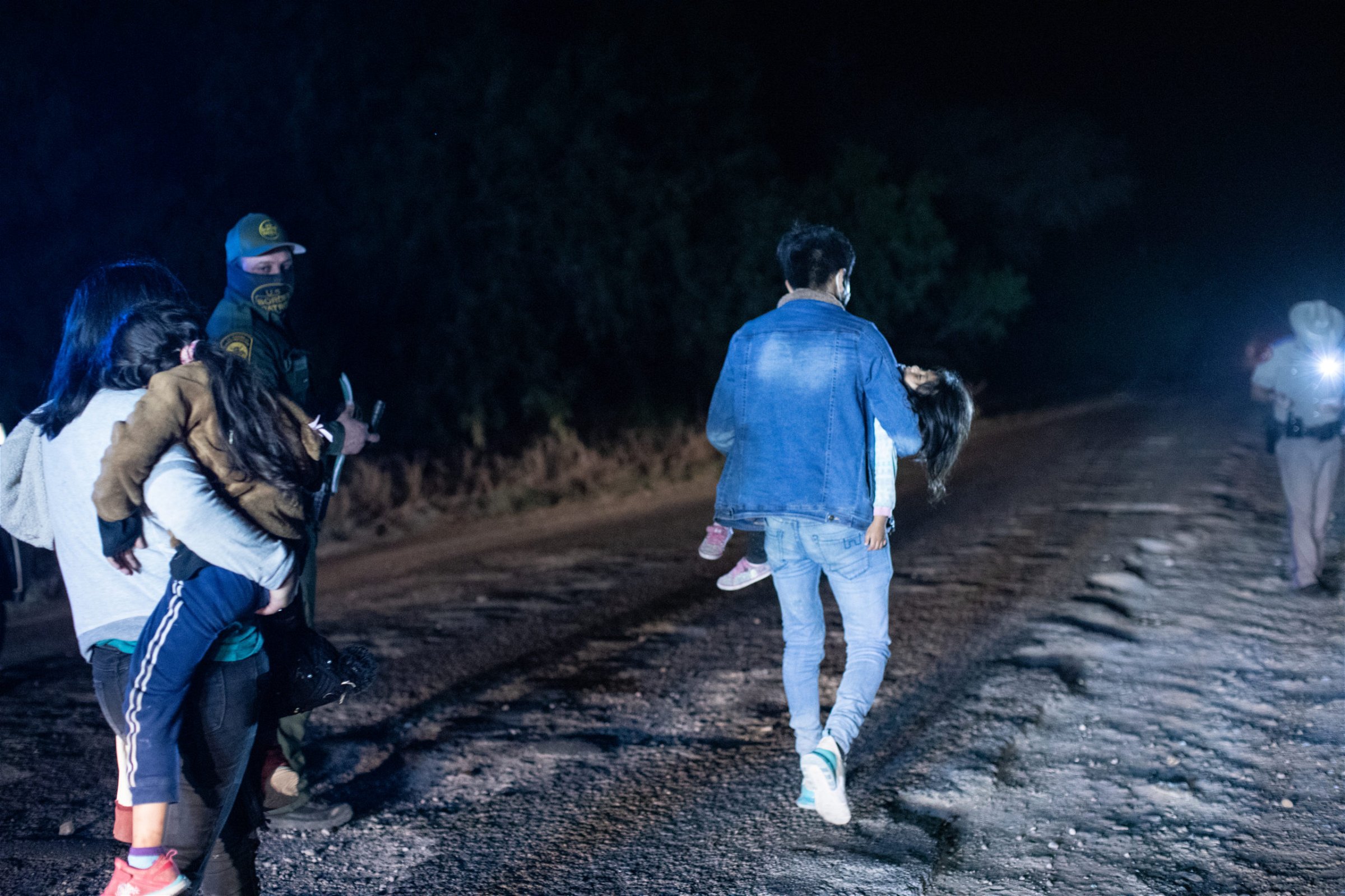 Illegal migrants walk towards law enforcement officials who gathered biometrical data from them before transporting them to a processing facility in La Joya, Texas, on March 25, 2021. (Kaylee Greenlee. - Daily Caller News Foundation)