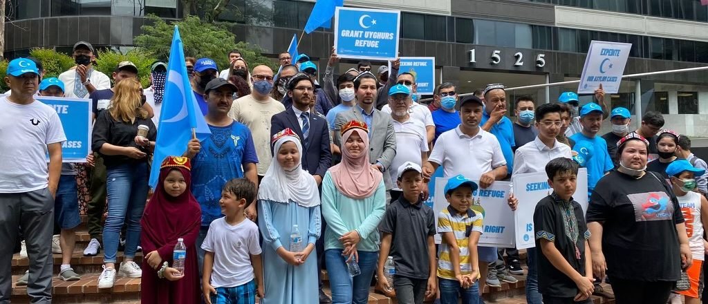 Hudayar (pictured center left) led a demonstration with ETNAM outside the Arlington Asylum Office urging the government to expedite Uyghur asylum cases in August 2021. (Photo courtesy of ETNAM)